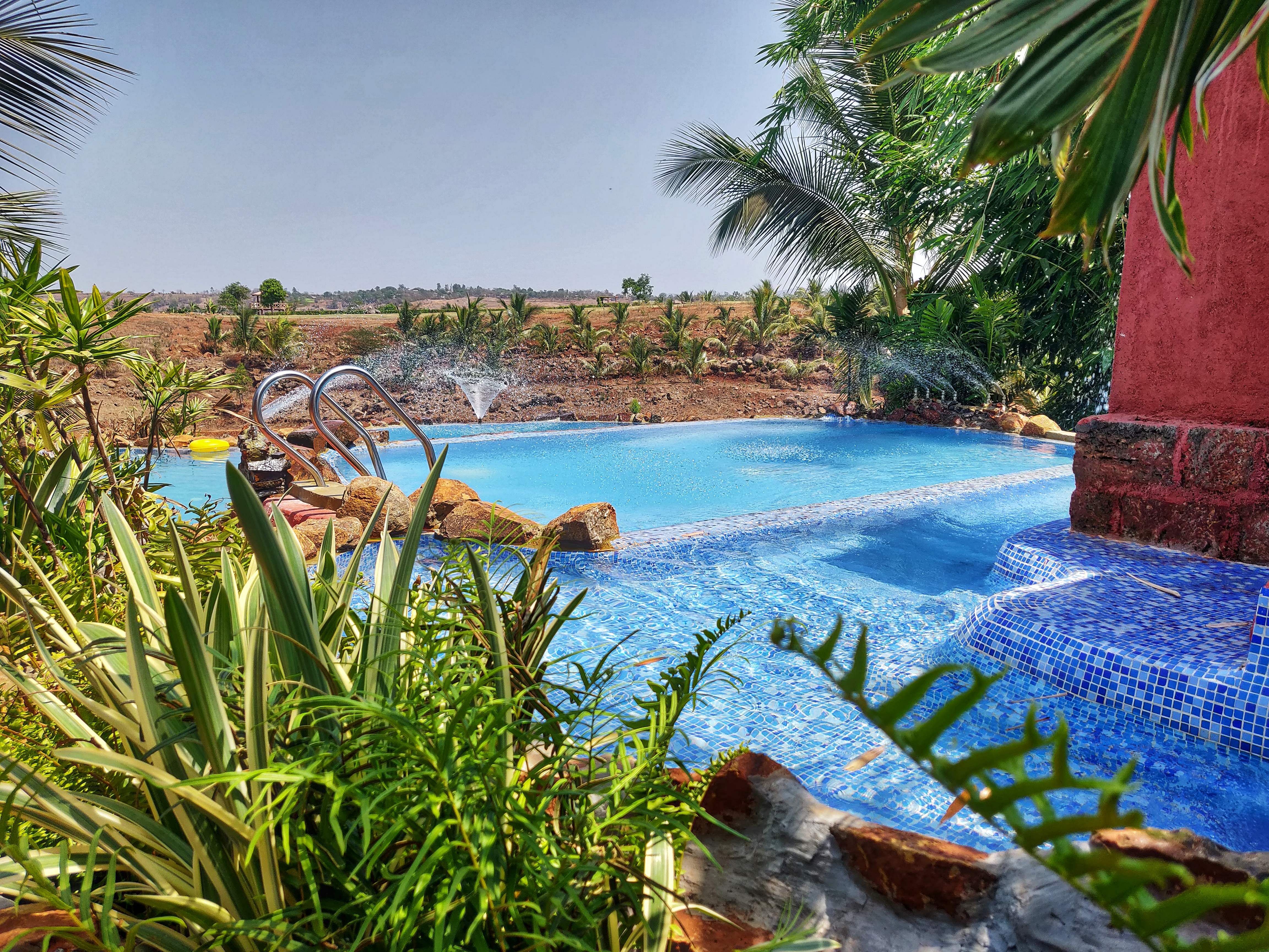 Swimming pool,Natural landscape,Vegetation,Majorelle blue,Azure,Resort,Property,Palm tree,Vacation,Water