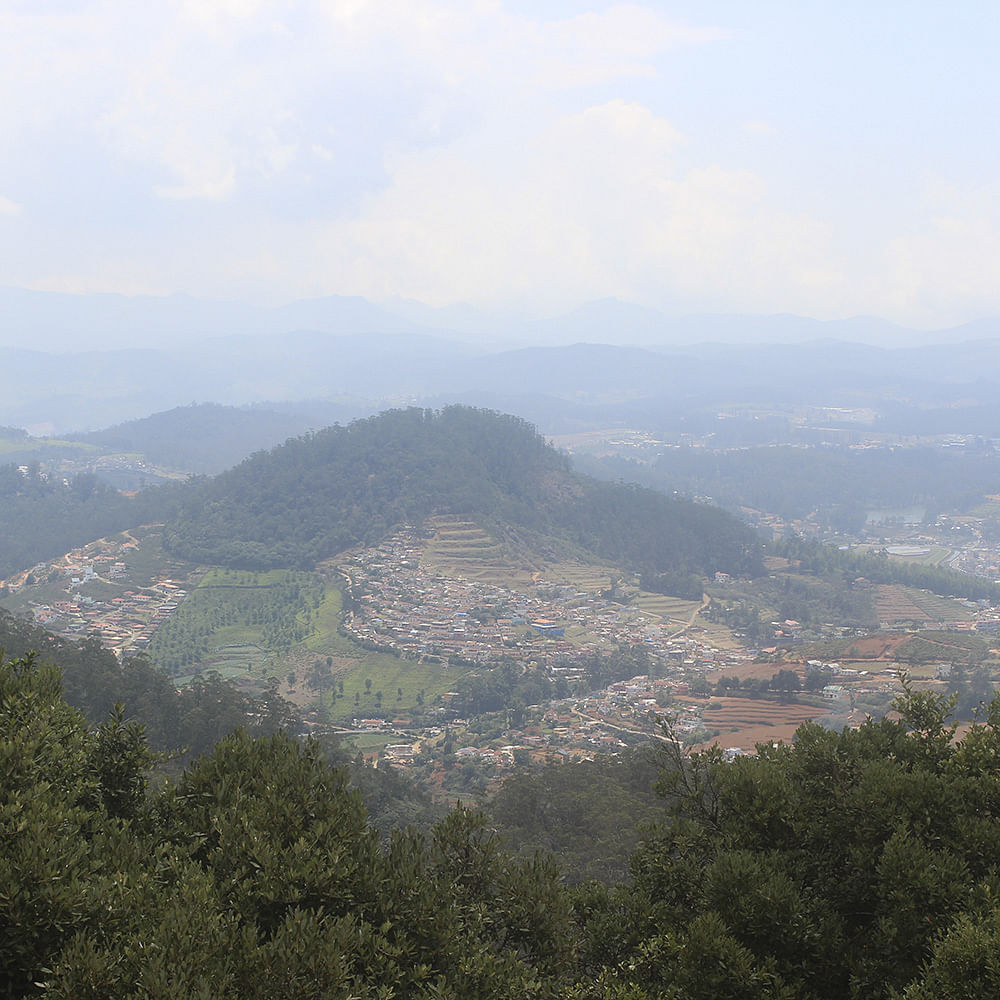 Hill station,Mountainous landforms,Sky,Atmospheric phenomenon,Mountain,Hill,Town,Highland,Tree,Cloud