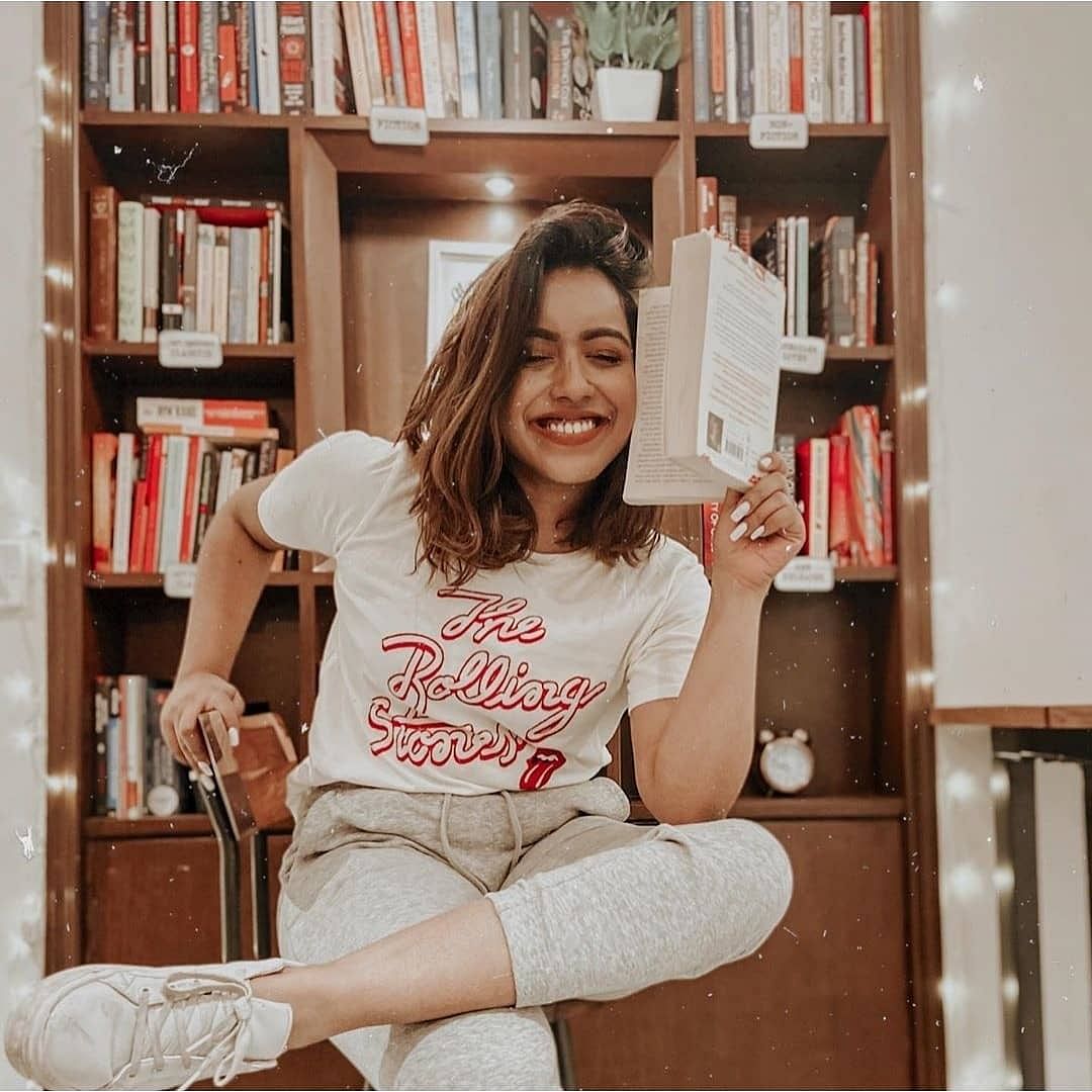 Furniture,Shelving,Bookcase,Sitting,Photography,Long hair,Brown hair,Shelf,Smile