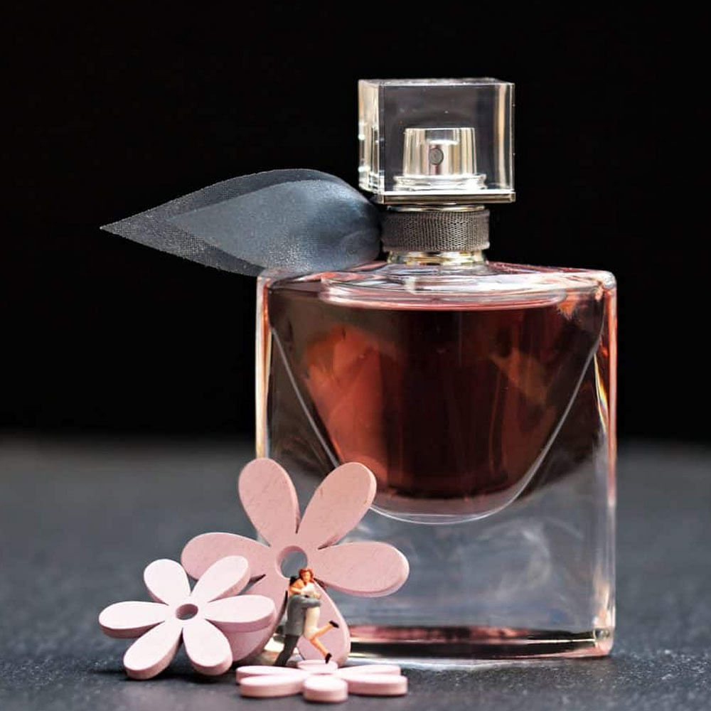 Perfume,Glass bottle,Bottle,Cosmetics,Pink,Liquid,Glass,Petal,Still life photography,Fluid