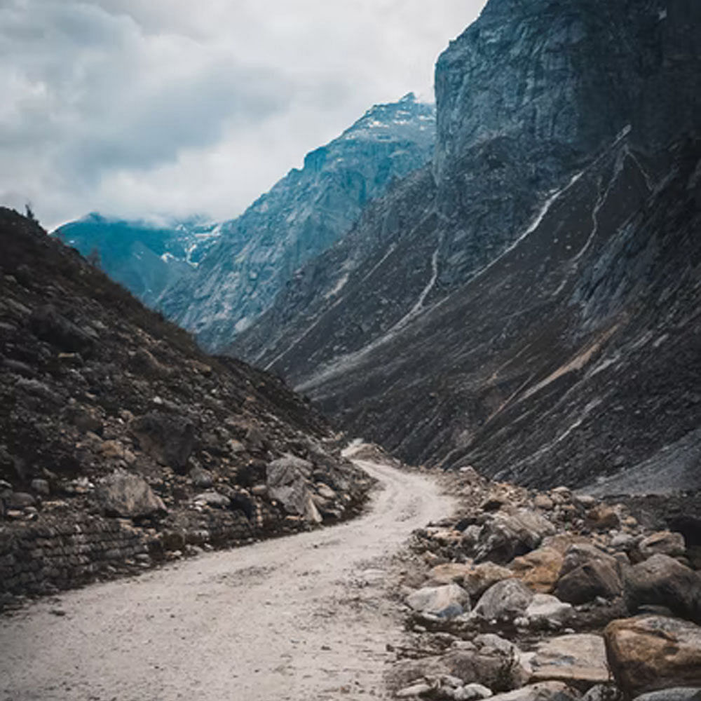 Sky,Cloud,Mountain,Slope,Natural landscape,Road surface,Mountain range,Tree,Bedrock,Landscape