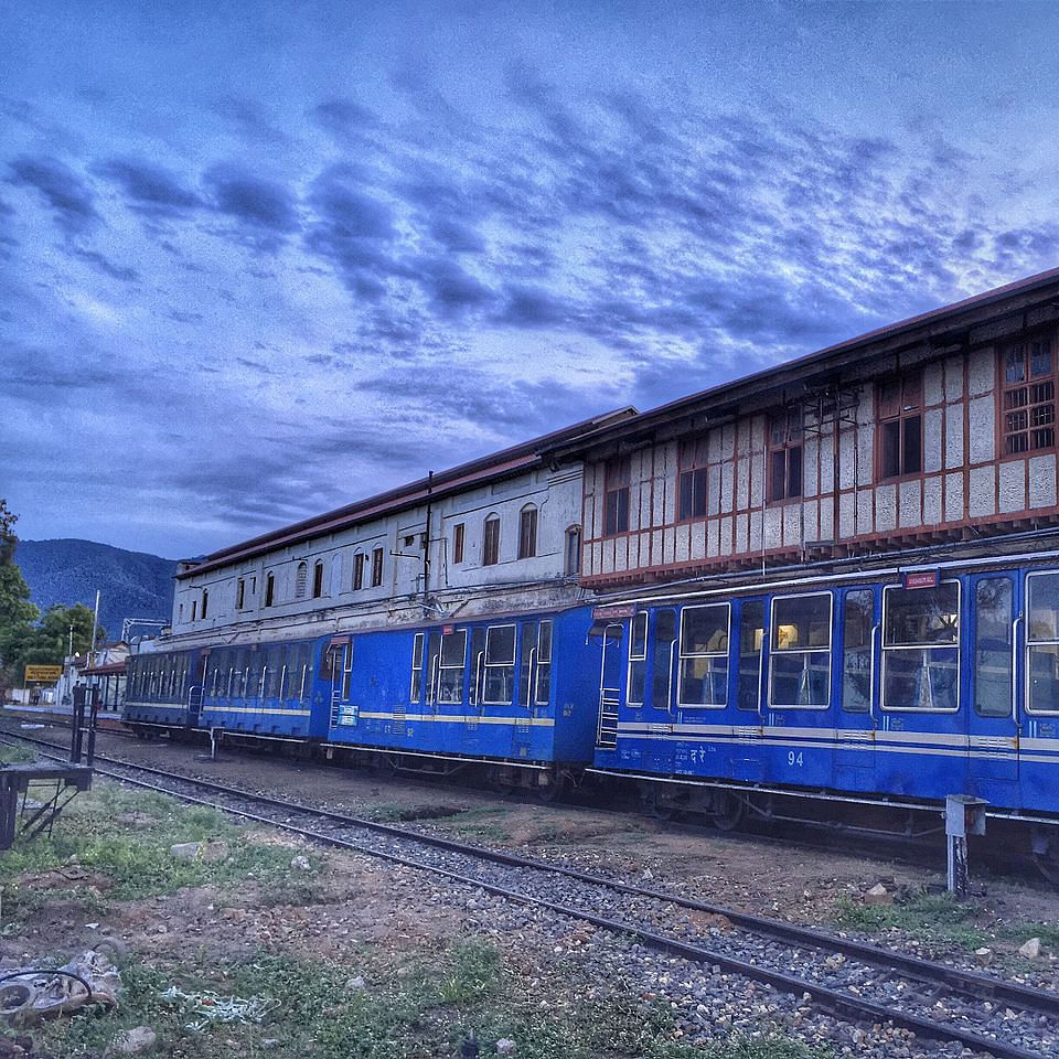 Cloud,Train,Sky,Window,Blue,Plant,Rolling stock,Track,Building,Tree