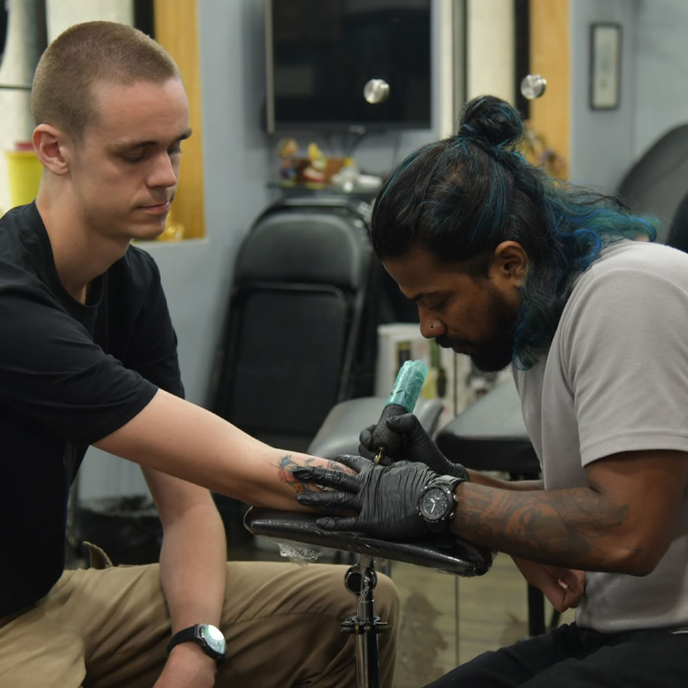 Arm,Hand,Tattoo,Wrist,Ear,Tattoo artist,Elbow,Watch,Beard,Facial hair